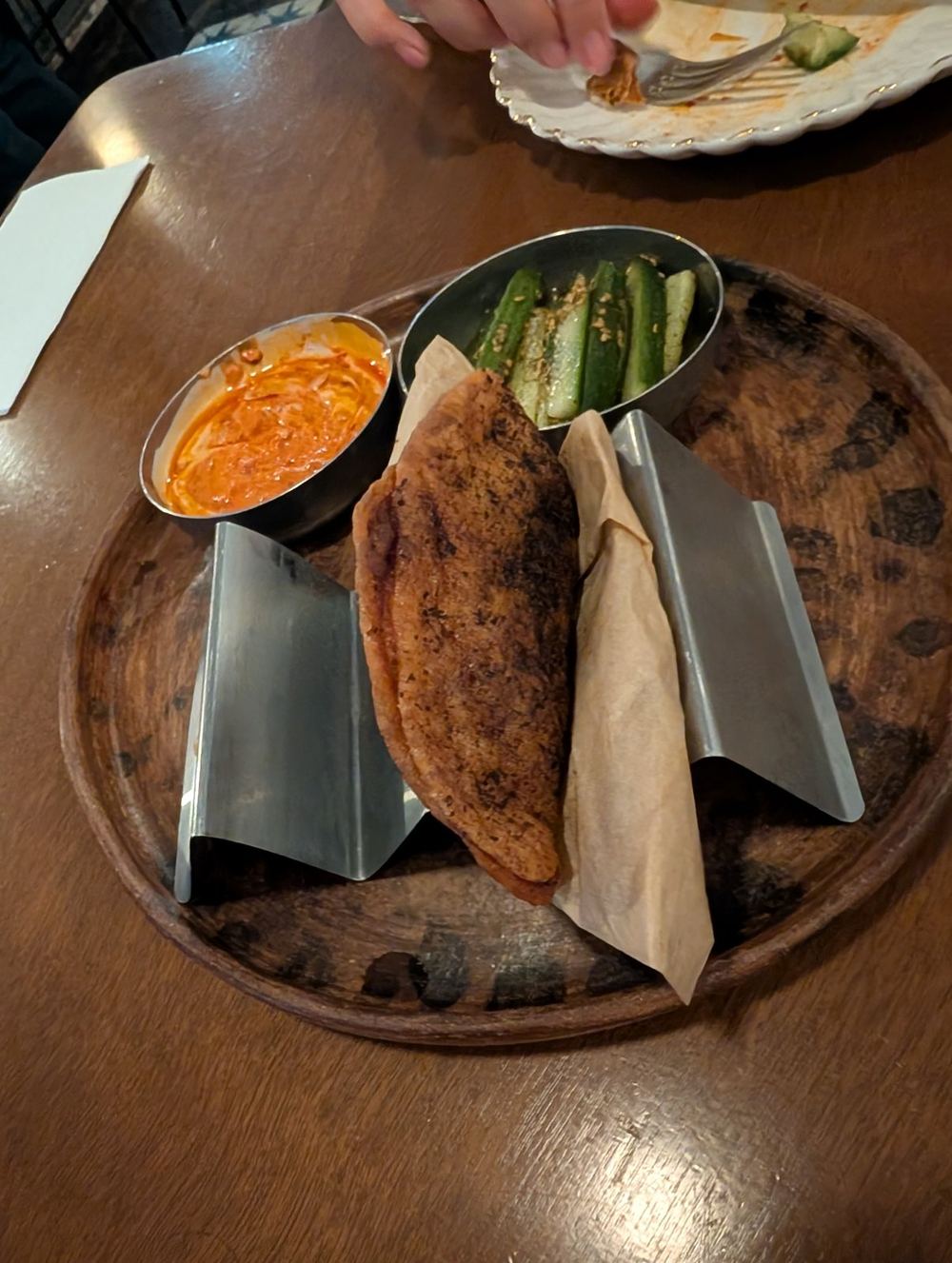 Crispy empanada with a spicy dip and pickled cucumbers