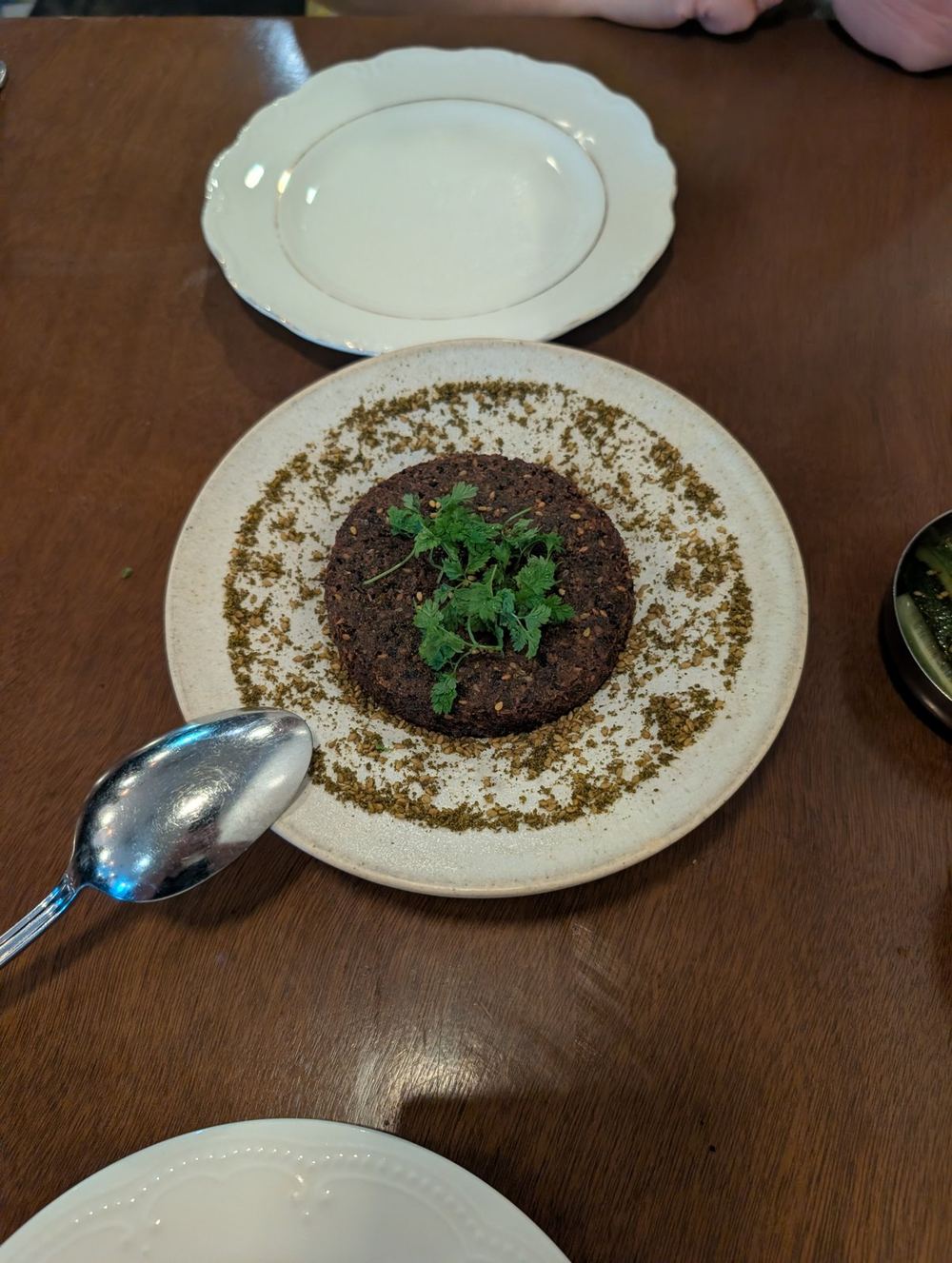 A large crusted falafel disk dusted in za'atar on tahini