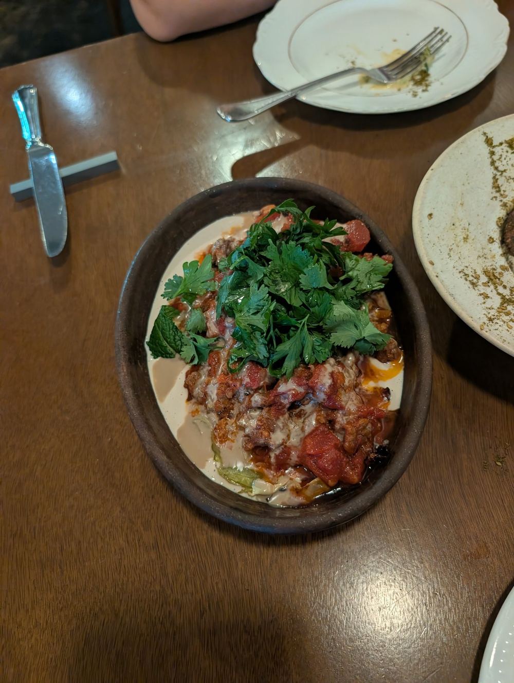 Stuffed cabbage under tomato, tahini and fresh herbs